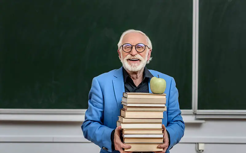 Man holding textbooks with an apple on top. Appears to be an academic, many careers in genealogy are academic.