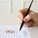 Photo of a hand holding a pen to sign a document