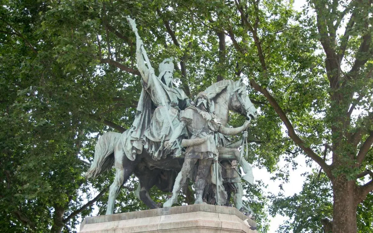 Photo of a statue of Charlemagne on a horse with large tree on background