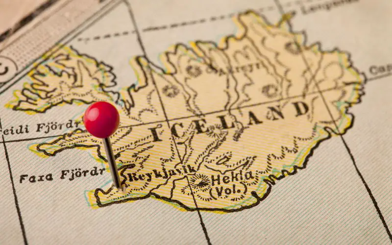 A map of Iceland in light brown color with red pin