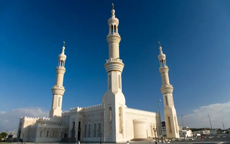Photo of a large white mosque with 3 tall towers