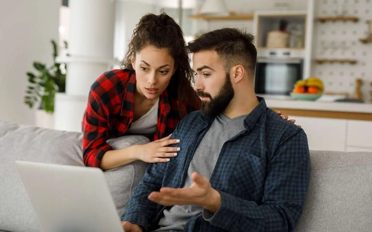 A man and womn looking at the laptop with a bit of surprise